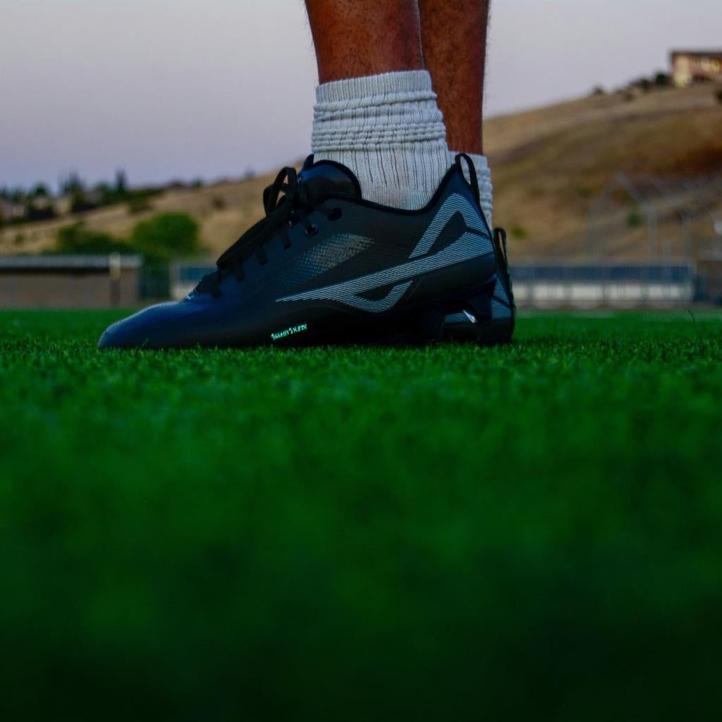 Caddix men’s low black/black football & lacrosse cleats in the turf that patented Smart Studs are designed to not lock your foot into, reducing leg injuries