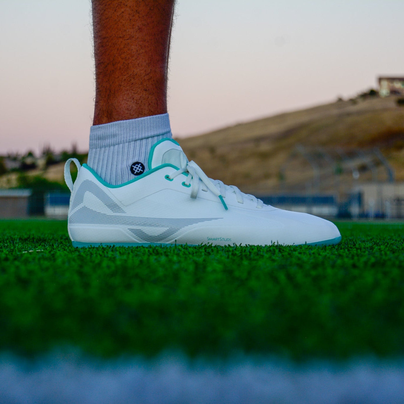 Side of Caddix men's teals low cut football lacrosse cleats for knee injuries in white teal