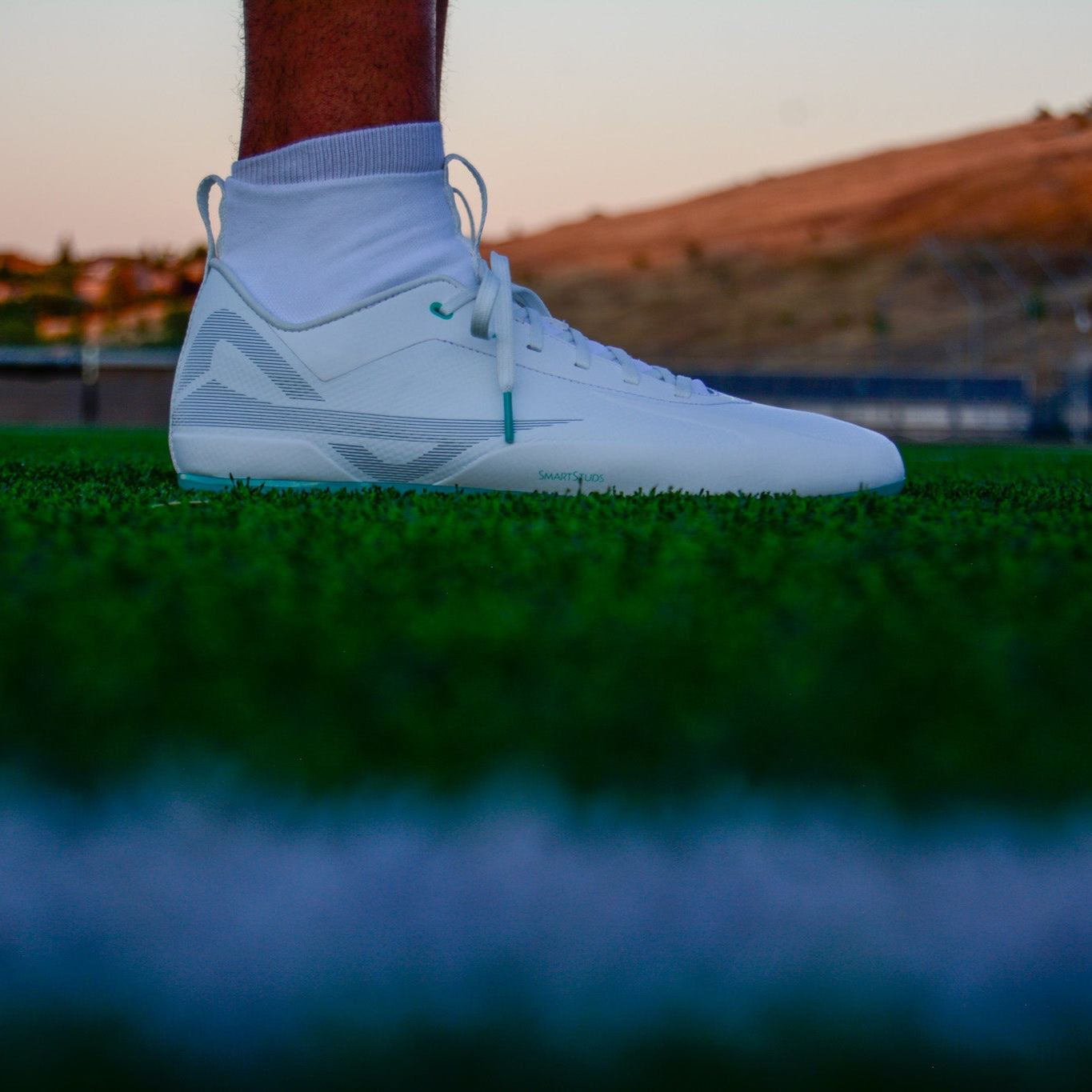 Side of Caddix men's teals mid cut football lacrosse cleats for knee injuries in white teal